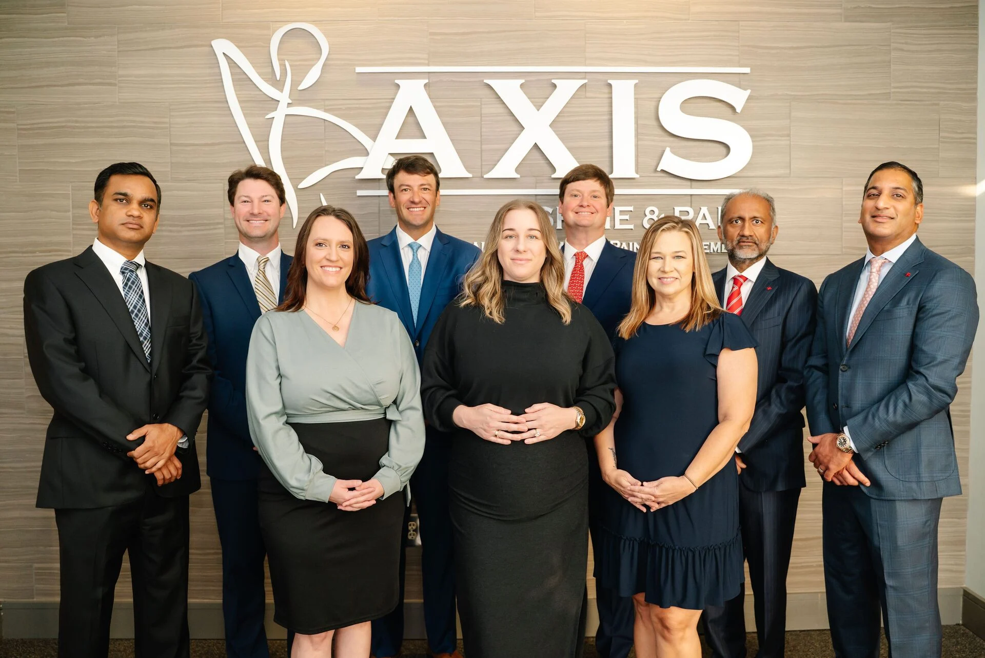 Axis Spine & Pain Center care team standing together in front of the clinic sign