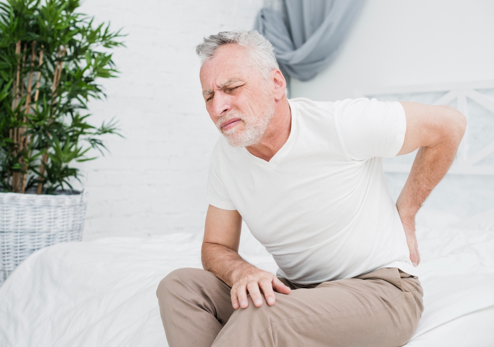 Middle-aged man experiencing lower back pain while sitting, a common symptom of chronic back conditions