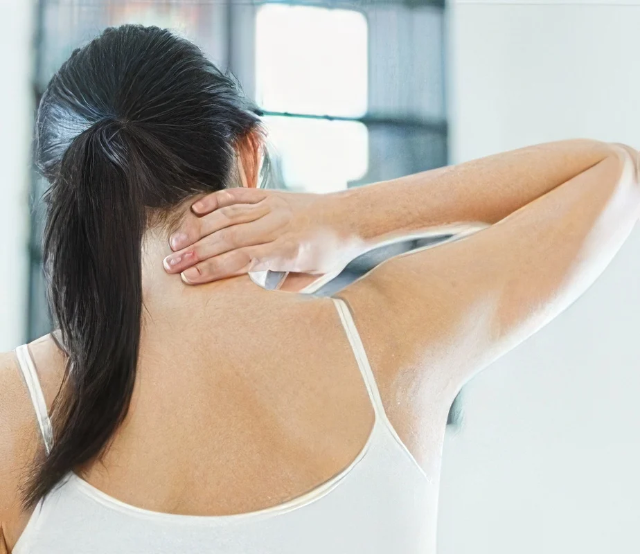 Woman holding the back of her neck and shoulder in discomfort