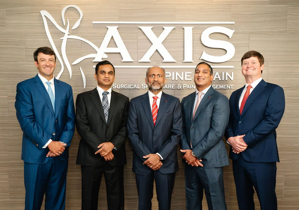 Axis Spine & Pain physicians standing in front of the clinic's Axis sign